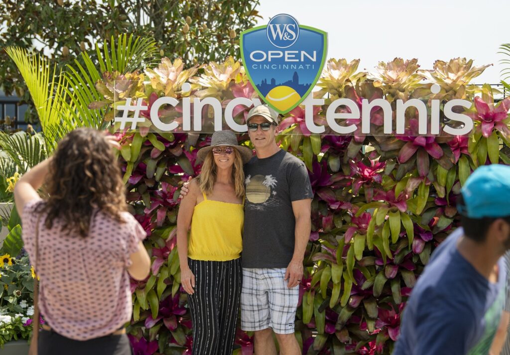 A couple posing in front of the #cincytennis sign