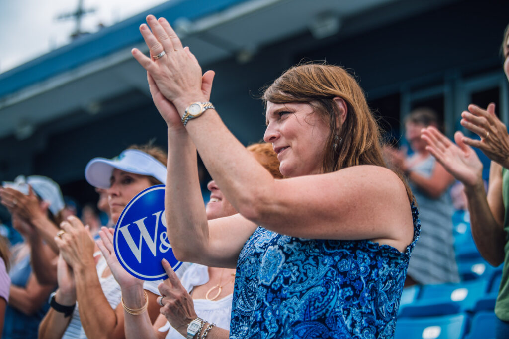 A fan clapping in the stands at a tennis match